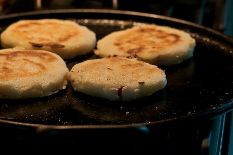 Arepas frying on a pan.