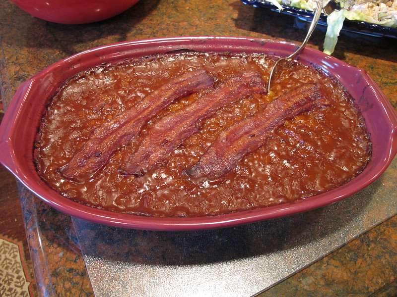 Baked beans in a baking dish. Strips of bacon are on top.