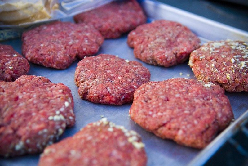 Uncooked burger patties on a baking tray.