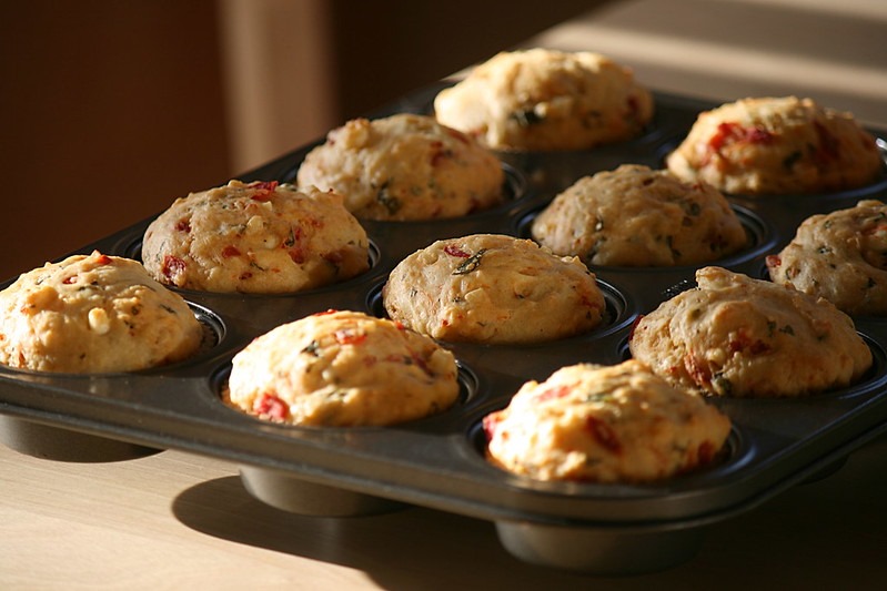 A muffin tin with 12 savory muffins, made with vegetables and cheese.