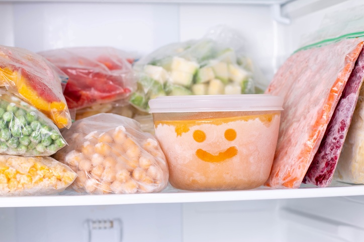 The inside of a stocked freezer. There is a tupperware full of soup, and serveral bags of prepped ingredients