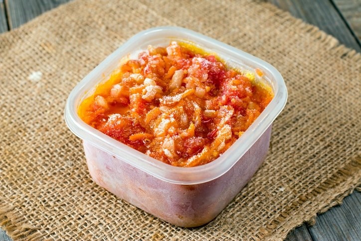 A tupperware filled with frozen pasta in tomato sauce