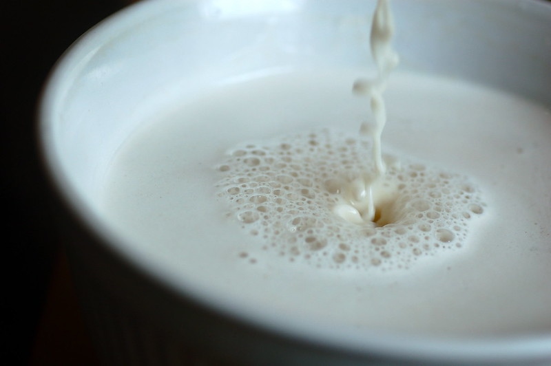 Oat milk being poured into a glass.