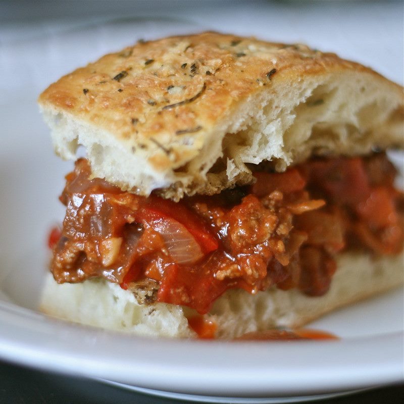 A sloppy joe on a plate; ground beef in tomato sauce on a bun