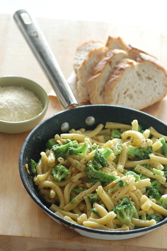 A pan full of tuna broccoli pasta. Bread and grated cheese are being served on the side.