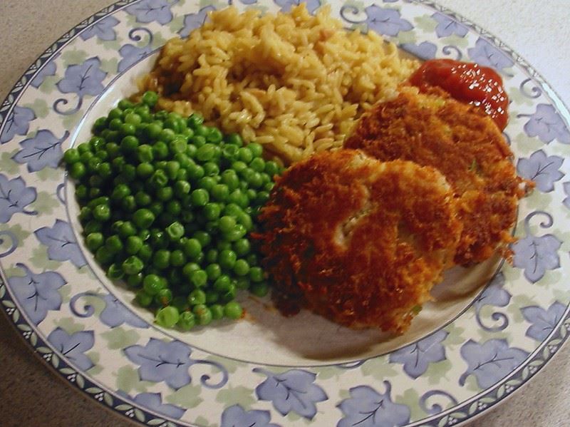 Tuna patties on a plate, with rice and peas on the side.